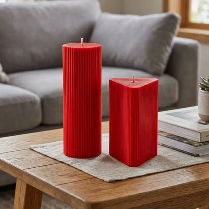 Geometric Pillar Candle Set featuring ribbed red triangle and tall column on a wooden table.