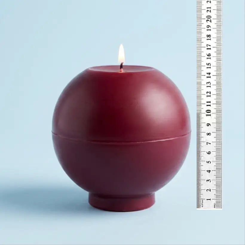 Round Candle - XL 1.65 kg in deep burgundy color, features a lit wick on a light blue background.