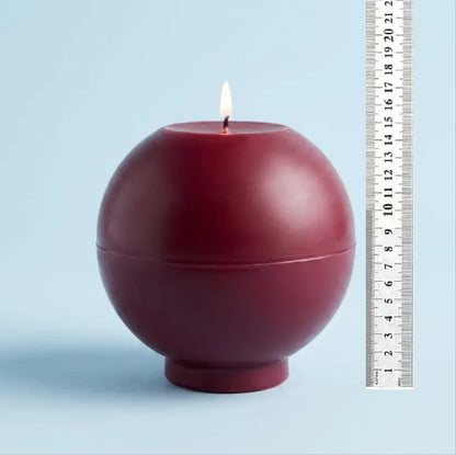 Round Candle - XL 1.65 kg in deep burgundy color, features a lit wick on a light blue background.