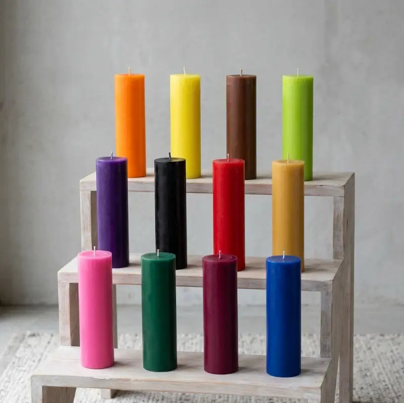 Colorful tall candles arranged on a wooden display, showcasing a variety of heights and hues for home decor.
