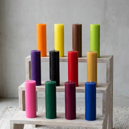 Colorful tall candles arranged on a wooden display, showcasing a variety of heights and hues for home decor.