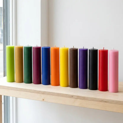 Collection of vibrant Tall Candles in various colors on a shelf, showcasing height and elegance.
