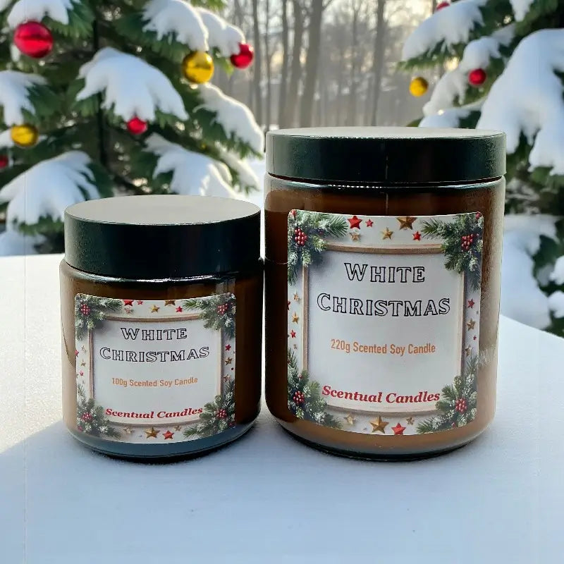 Two White Christmas scented candles on a snowy surface with Christmas trees in the background.