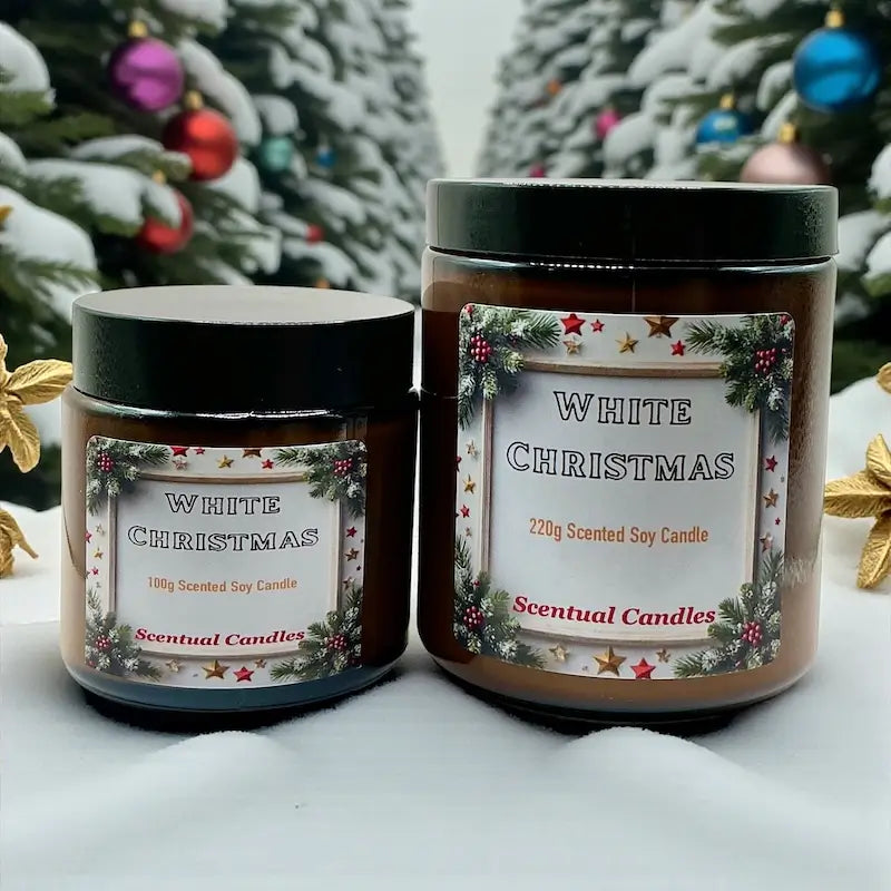 Two White Christmas scented candles from Scentual Candles on a snowy background with Christmas trees.