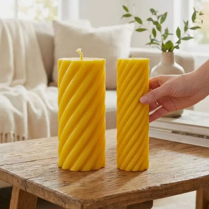 Pillar Candle Set featuring two yellow spiral column candles on a wooden table in a cozy living space.