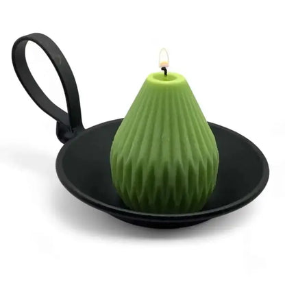 Green pear-shaped candle on a black chamberstick candle holder against a white background