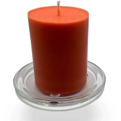 Transparent glass candle holder plate with orange pillar candle, showcasing elegant and heatproof design for versatile use on tabletops and special occasions.