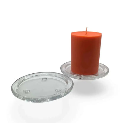 Round transparent glass candle holder plate with orange candle displayed.