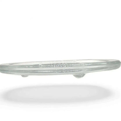Transparent round glass candle holder plate with small feet for stability.