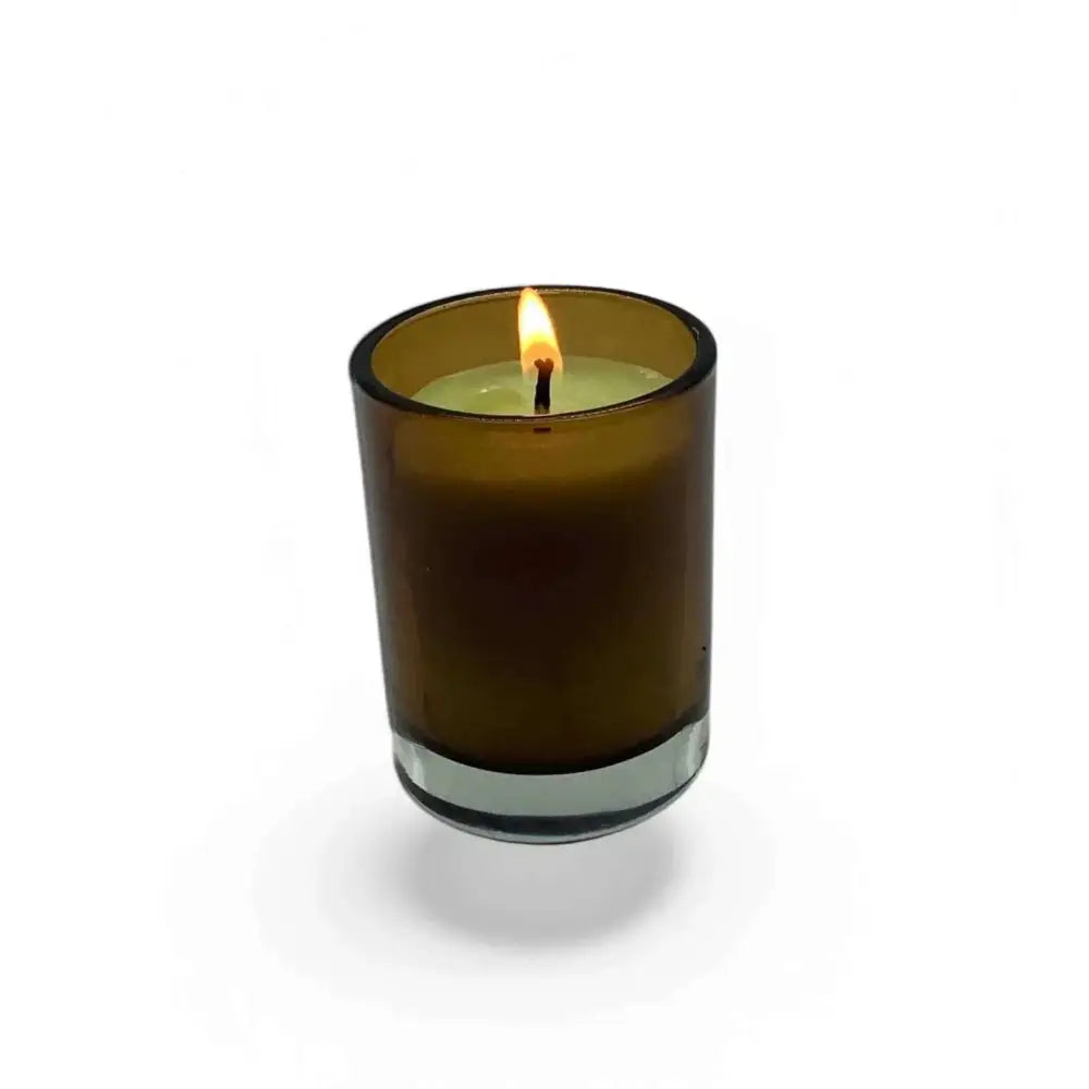 Amber glass votive candle holder with a lit candle, enhancing a cozy ambiance.
