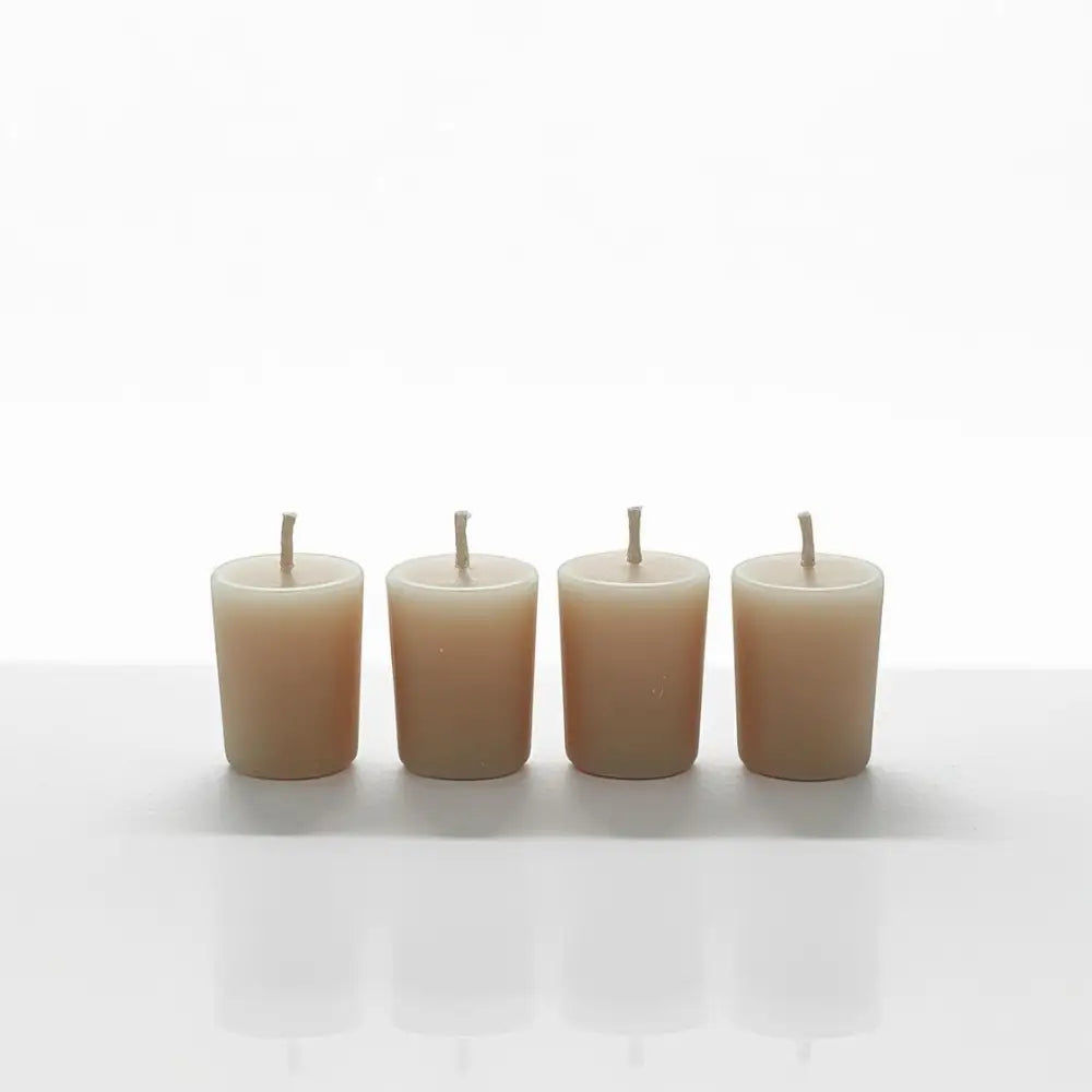 Set of four Vanilla Votive Candles made from scented soy wax, placed on a reflective surface.