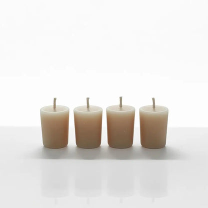 Set of four Vanilla Votive Candles made from scented soy wax, placed on a reflective surface.