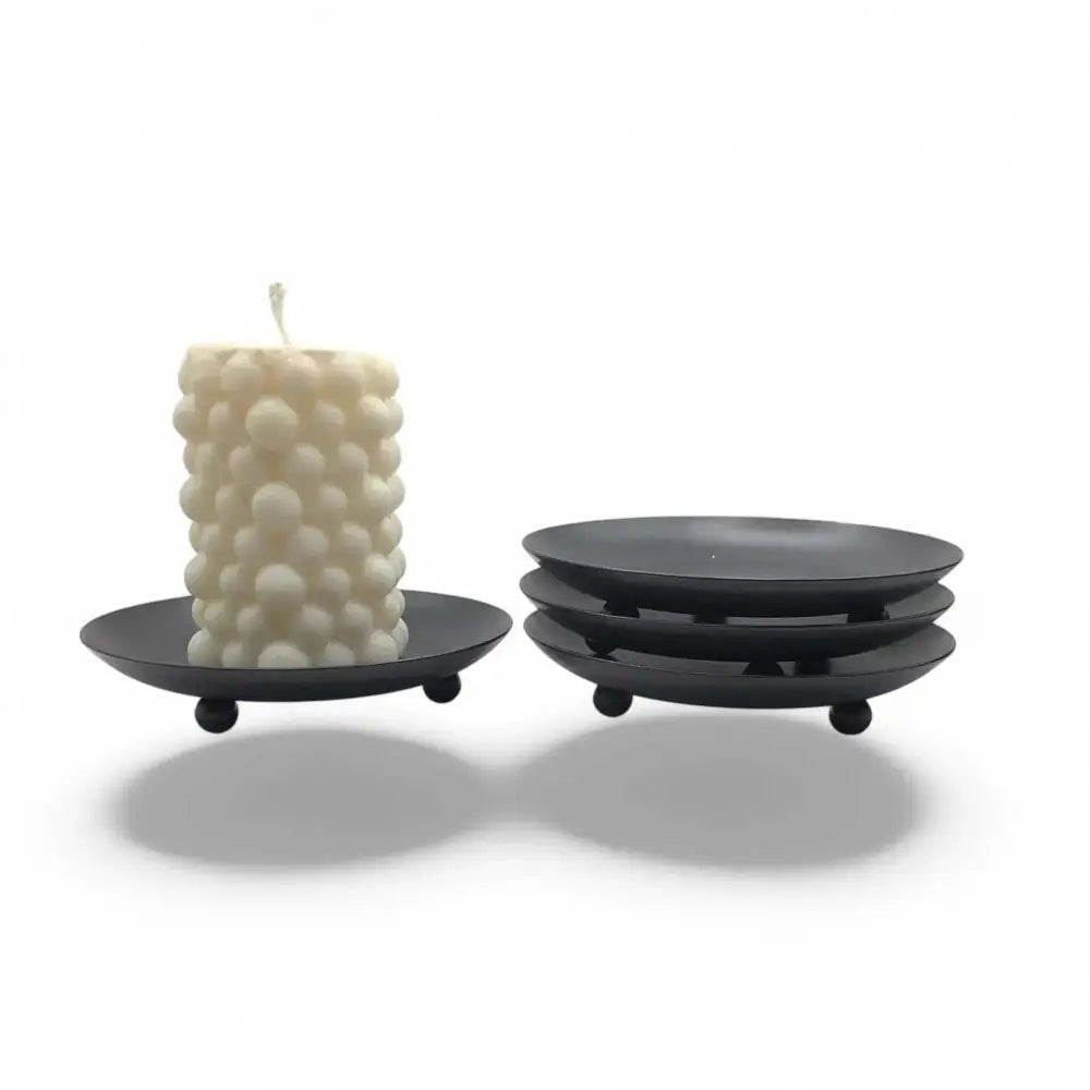 Round wrought iron candle holder with matte black finish and upward lipped edge for wax prevention, showcasing minimalist Nordic design.